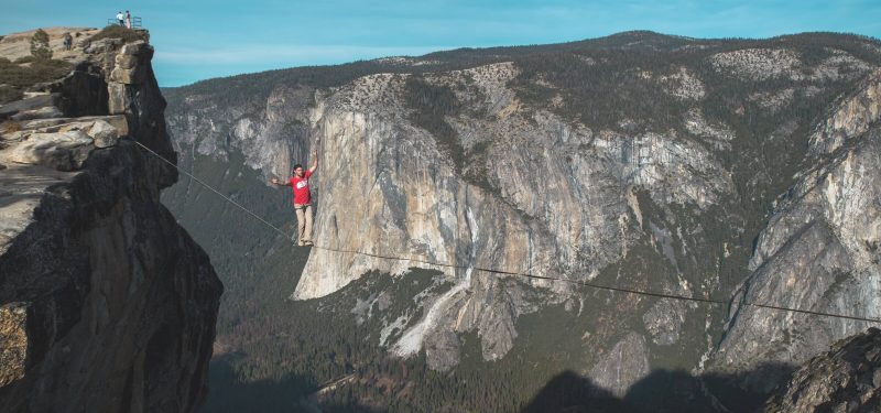 Man in red t-shirt walking a highline at Taft Point, Yosemite.