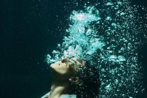 Woman underwater in suit with air bubbles